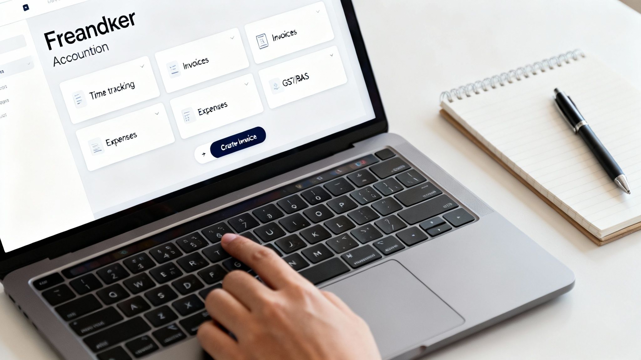 A person's hand typing on a laptop showing 'Freandker' accounting software with a notebook and pen nearby.